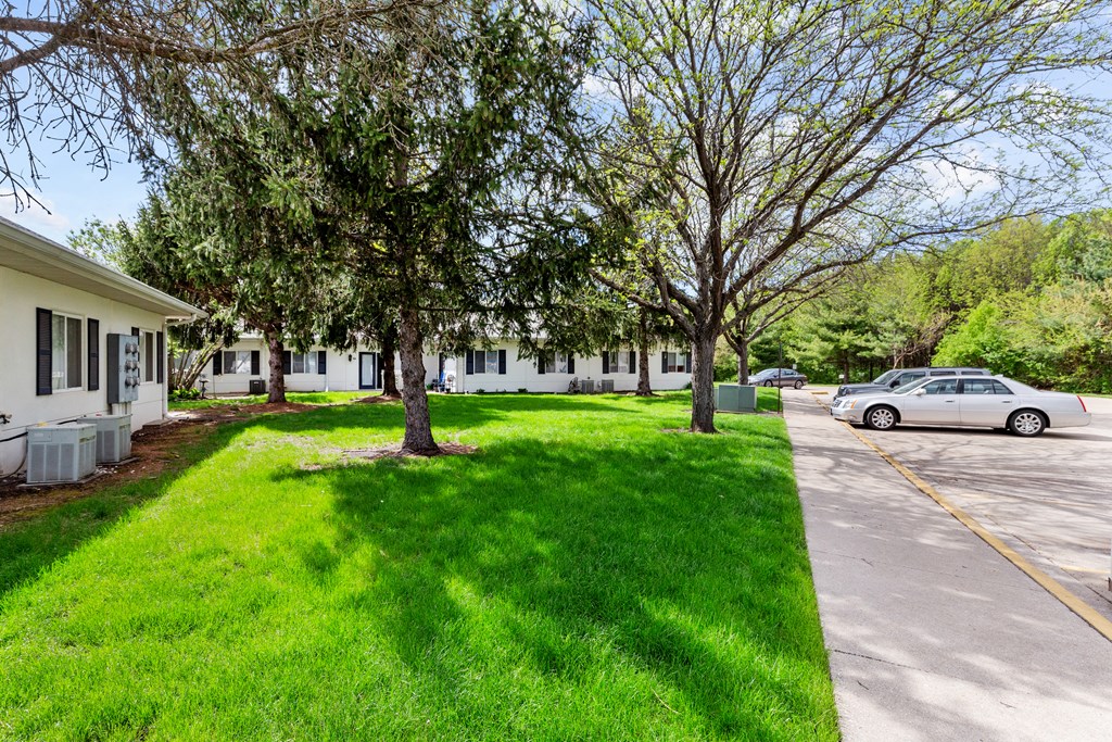 a white car parked in front of a house with trees