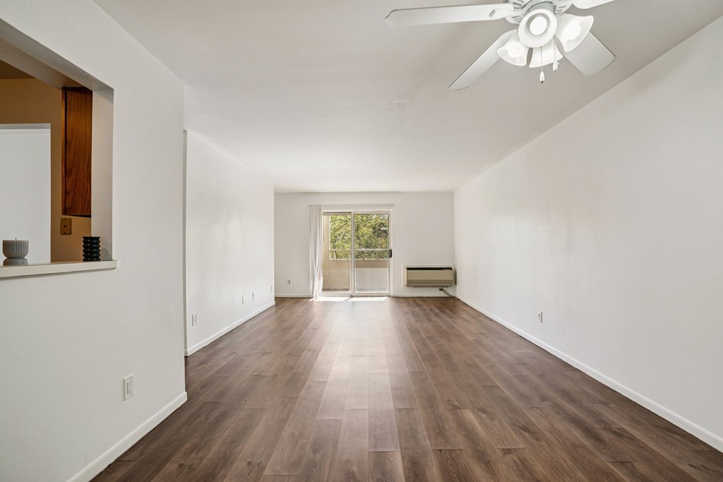 A room with a ceiling fan and wooden flooring.