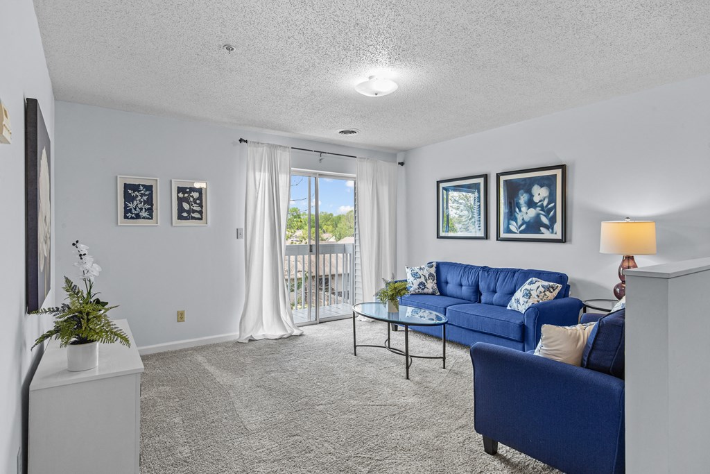 a living room with blue couches and a glass coffee table