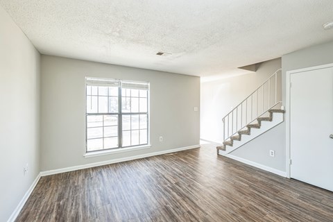 A room with a wooden floor and a staircase.
