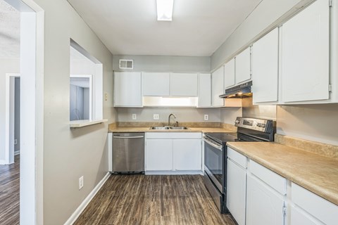 A kitchen with white cabinets and a wooden counter top.