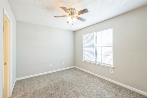 A room with a ceiling fan and a window with blinds.