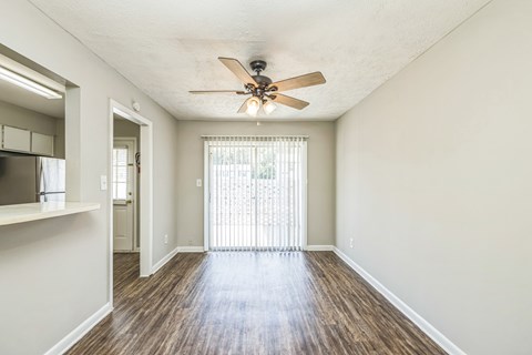 A room with a ceiling fan and sliding glass doors.