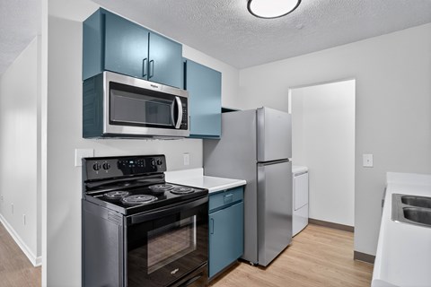 A kitchen with a black stove and blue cabinets.