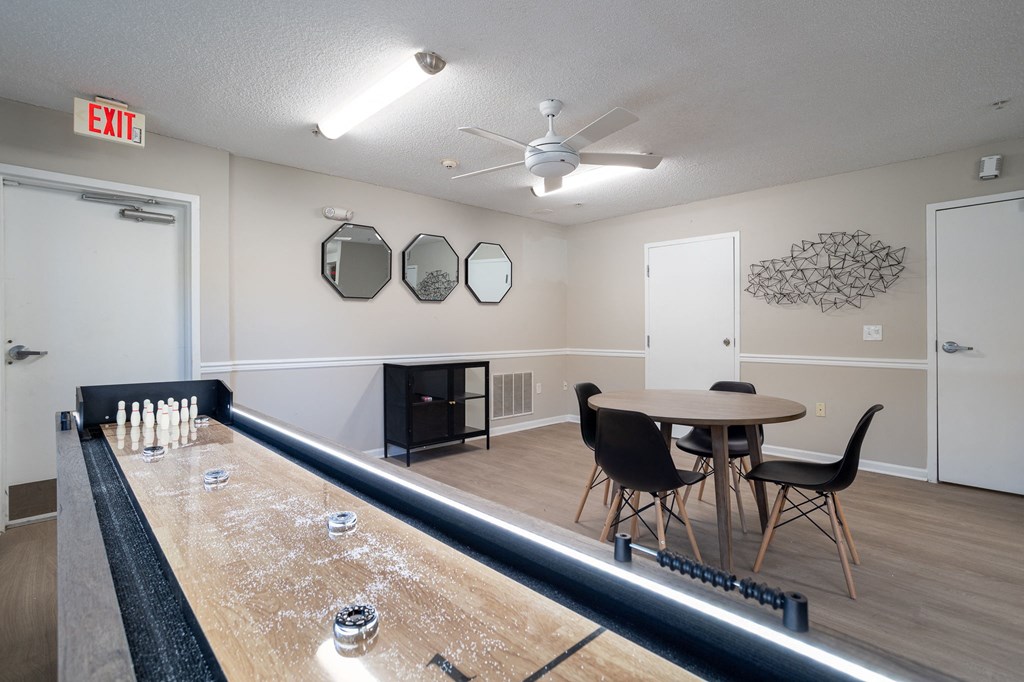 a recreation room with a shuffleboard table and chairs
