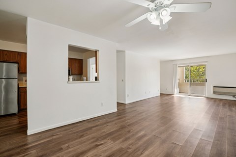 A spacious living room with a ceiling fan and hardwood floors.
