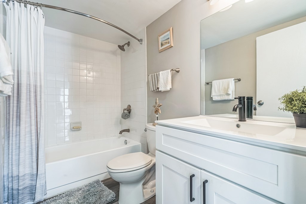 A white bathroom with a toilet, sink, and shower.