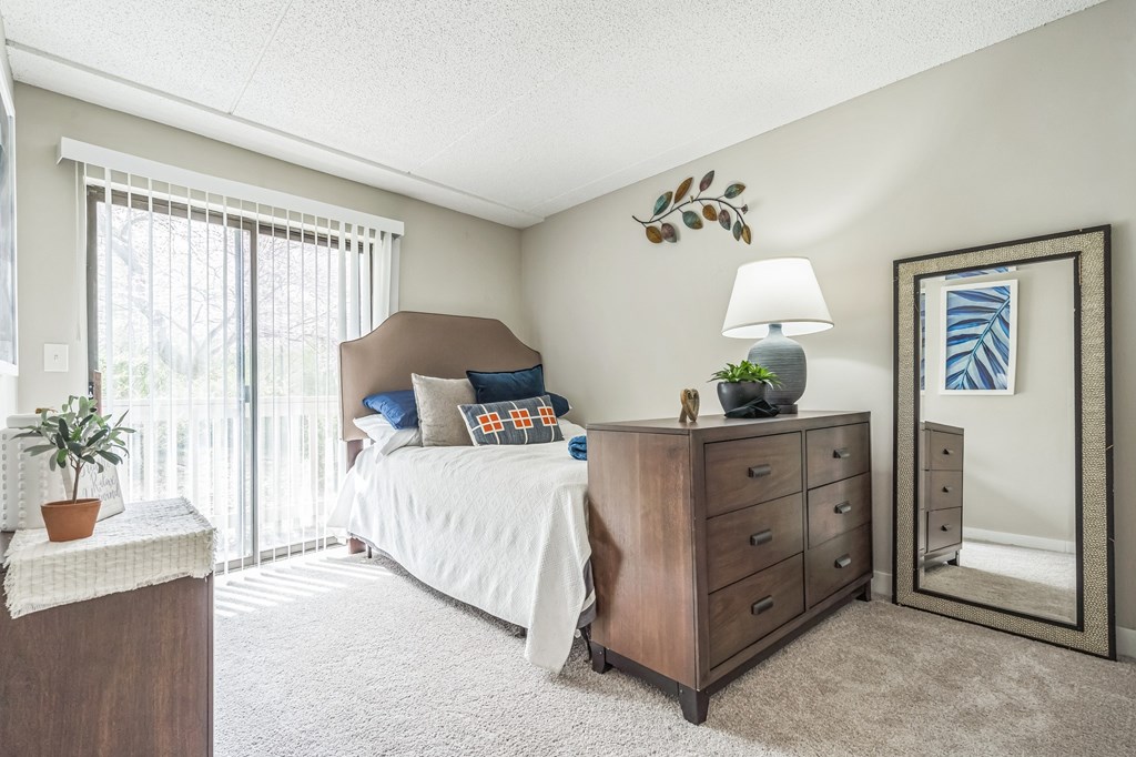 A bedroom with a bed, dresser, and mirror.
