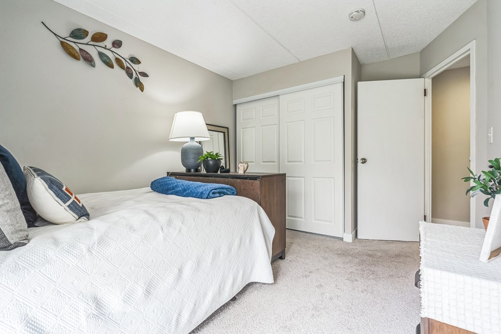 A bedroom with a large bed and a lamp on the side table.