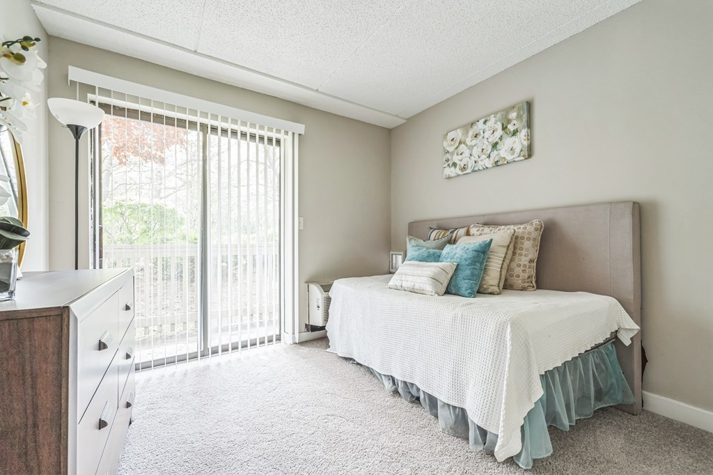 A bedroom with a bed, dresser, and window with blinds.