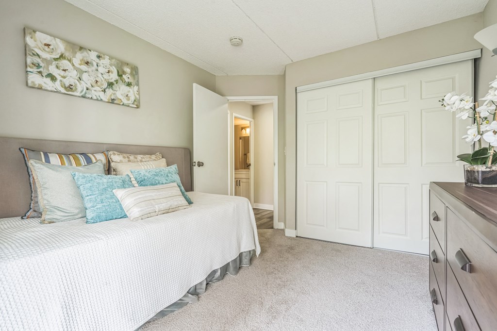 A bedroom with a bed, dresser and a painting on the wall.