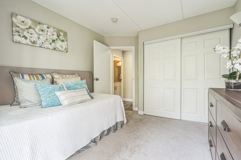 A bedroom with a bed, dresser and a painting on the wall.