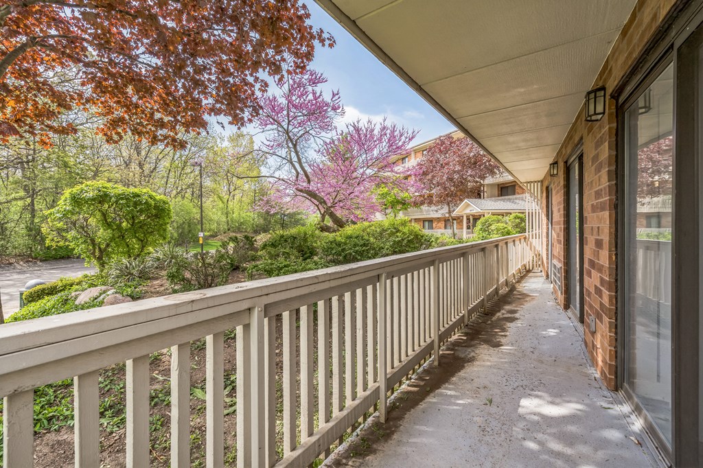 A balcony with a railing and a view of a garden and houses.