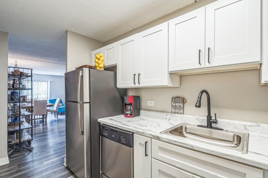 A kitchen with a refrigerator, dishwasher, and sink.