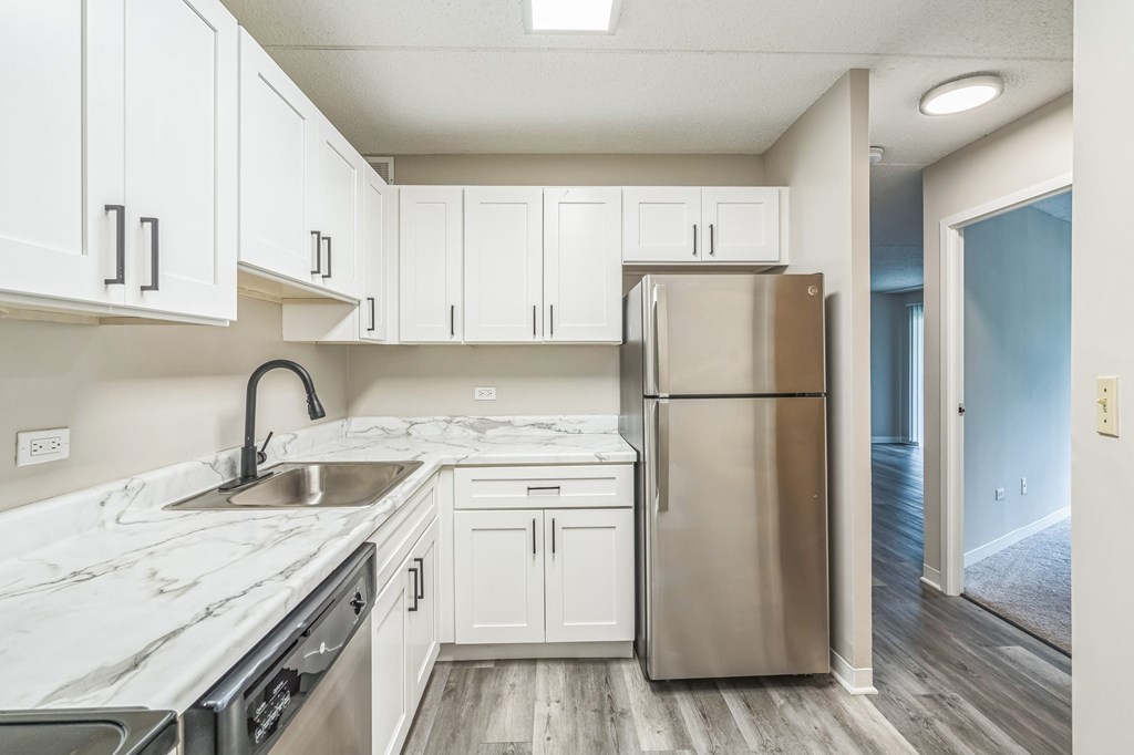 A kitchen with white cabinets and a stainless steel refrigerator.