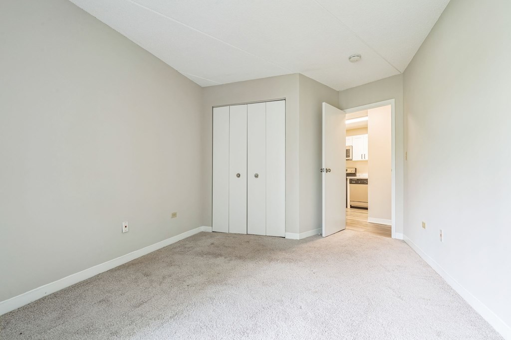 A room with a white door and a carpeted floor.