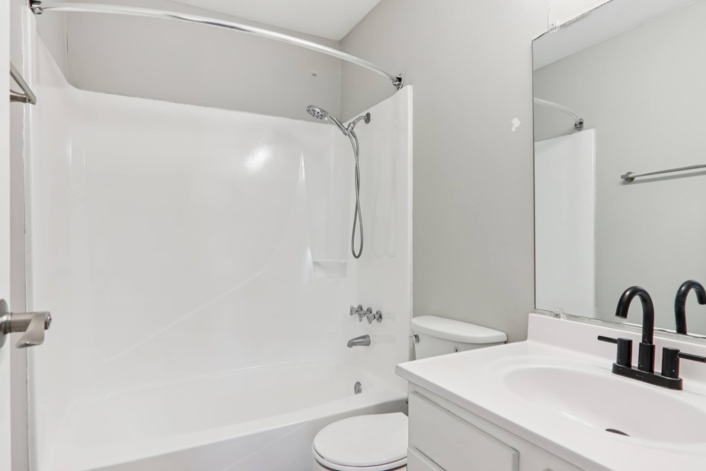 A white bathroom with a toilet, sink, and shower.