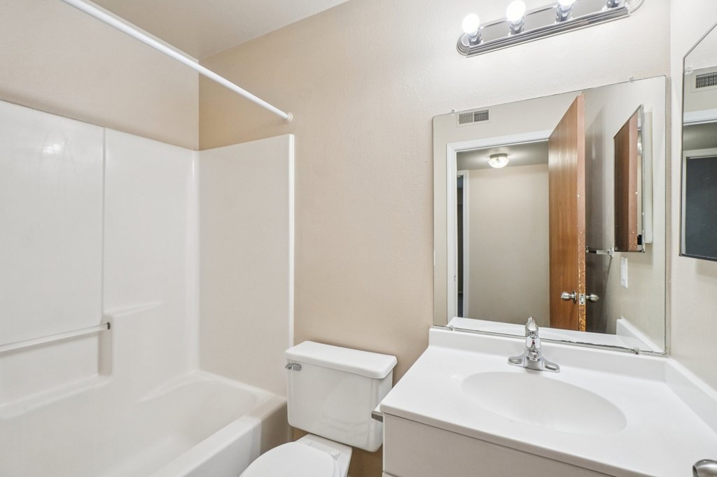 A white bathroom with a toilet, sink, and bathtub.