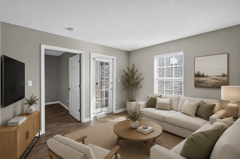 A living room with a white couch, a wooden coffee table, and a television on a cabinet.