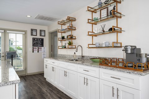 A kitchen with white cabinets and a marble countertop.