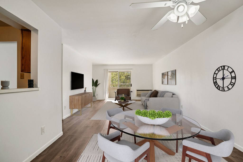 A modern living room with a glass table and white chairs.