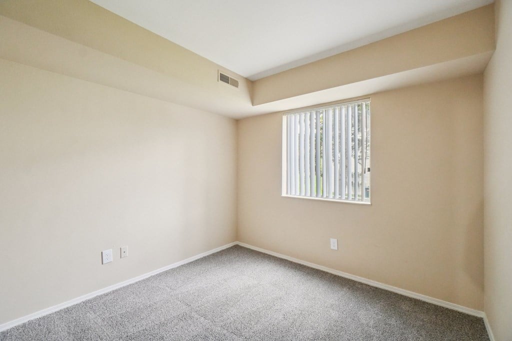 A room with a window covered by a white blind.