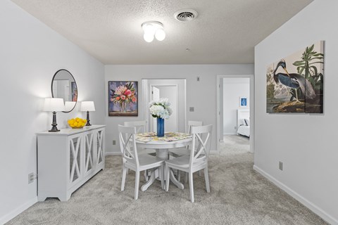 a dining room with a table and chairs and a mirror in a house
