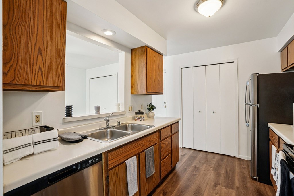 A kitchen with wooden cabinets and a stainless steel dishwasher.