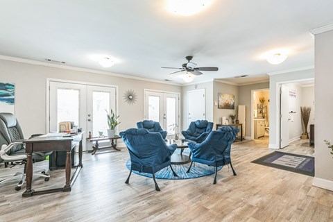 A living room with a blue chair and a ceiling fan.