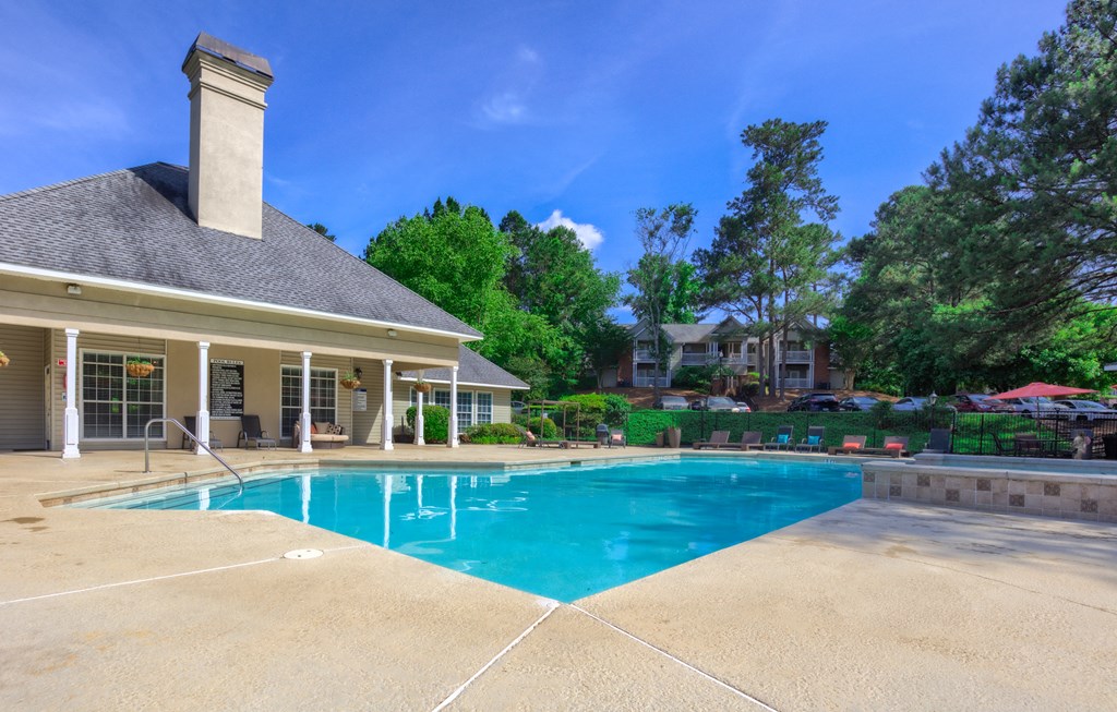 a swimming pool with a house and trees in the background