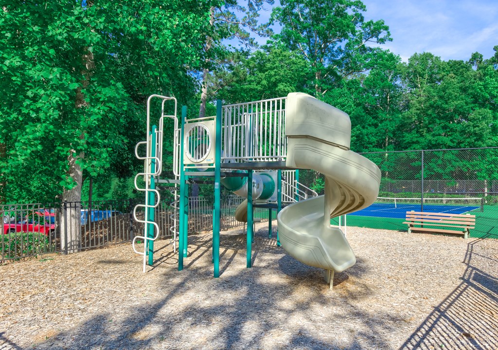 a slide at a playground with trees in the background