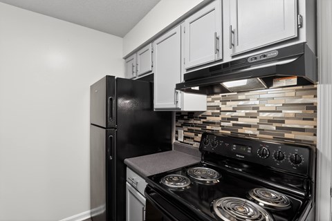 A black refrigerator and stove in a kitchen.