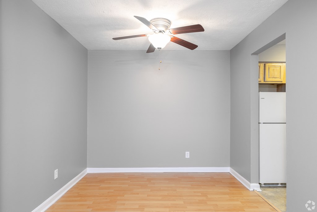 an empty room with a ceiling fan and a refrigerator