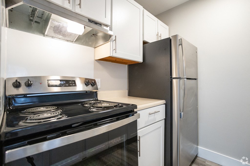 a kitchen with white cabinets and stainless steel appliances and a refrigerator