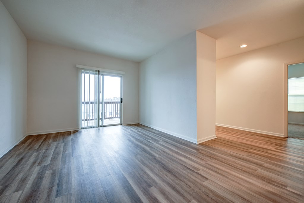 an empty living room with wood flooring and a balcony