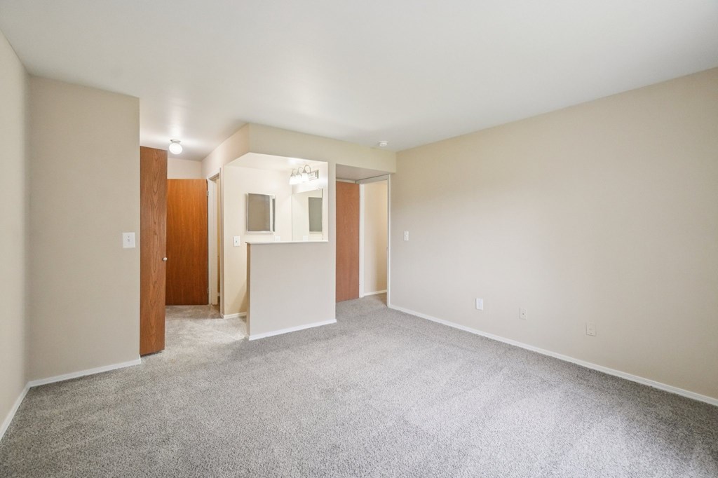 A spacious room with a carpeted floor and a door on the left side.