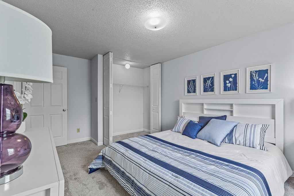 a bedroom with a bed and white walls and blue and white bedding
