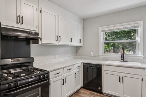 A kitchen with white cabinets and a black stove top oven.