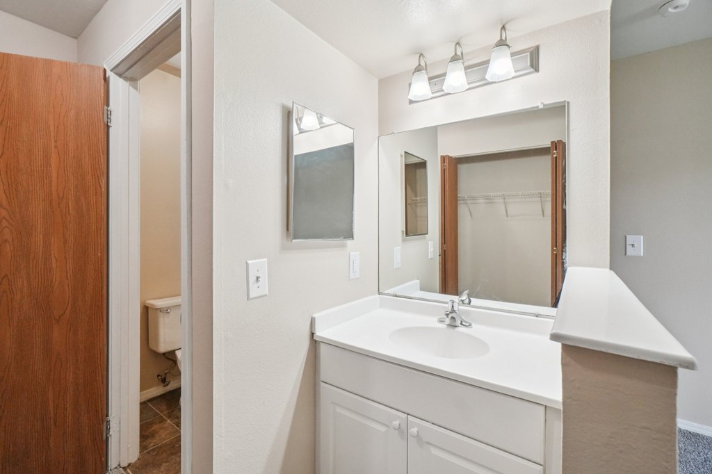 A bathroom with a sink, mirror, and light fixture.