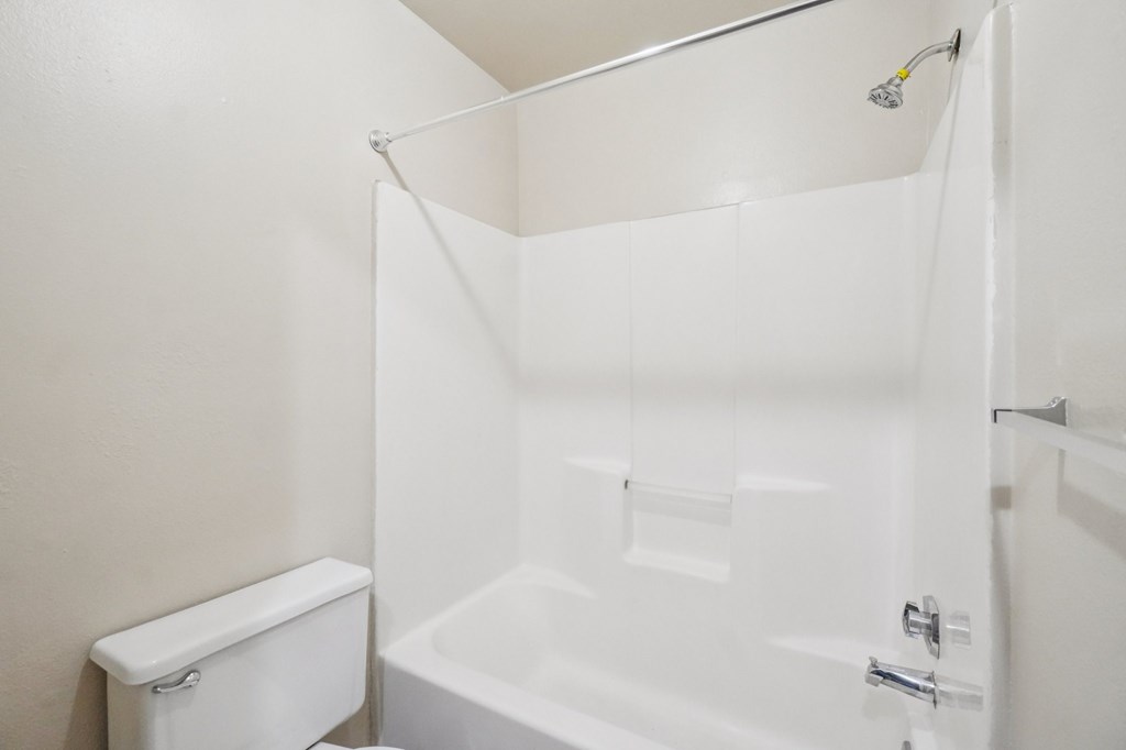 A white bathroom with a toilet, tub, and shower.