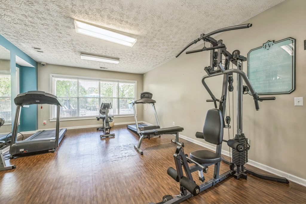 A home gym with a treadmill, elliptical trainer, and a stationary bike.