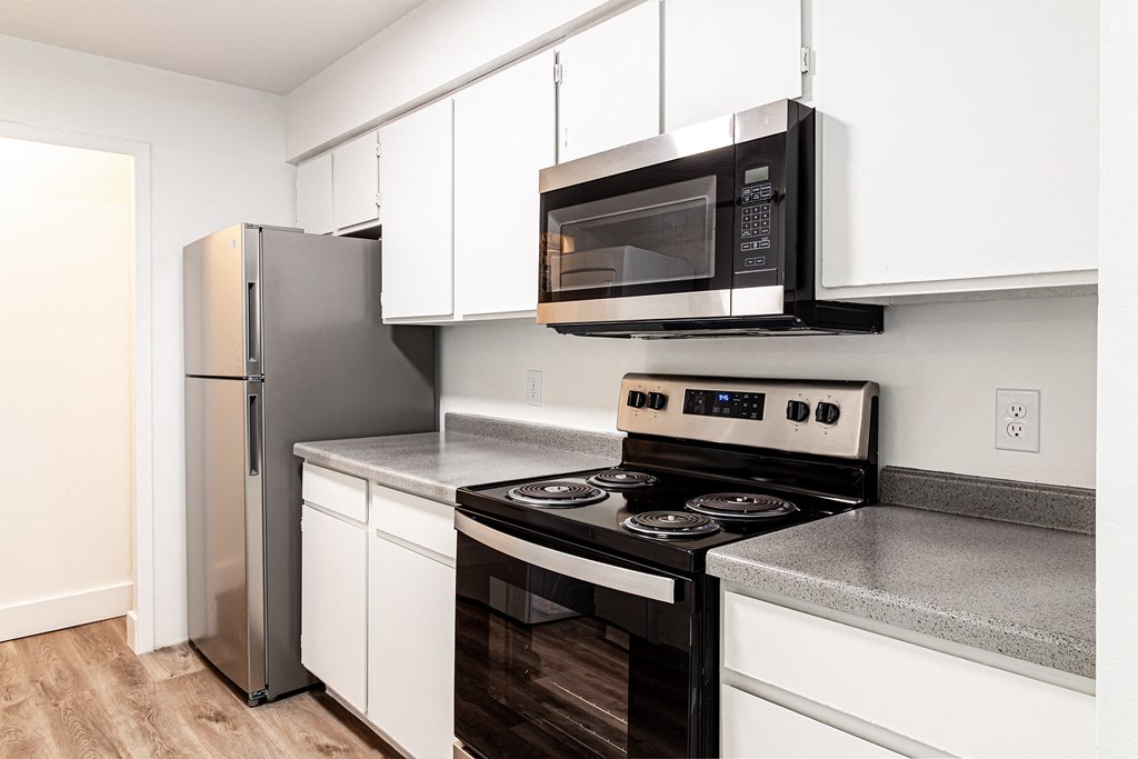 a kitchen with white cabinets and a black stove and a microwave