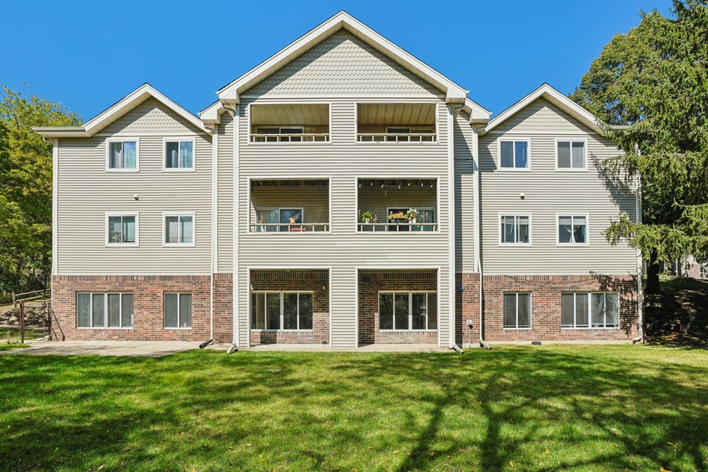 A large two-story house with a grey facade and a green lawn in front.