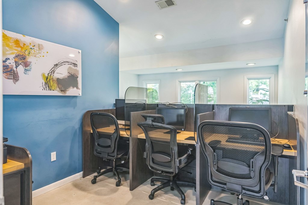 A room with blue walls and four black chairs with desks in front of them.