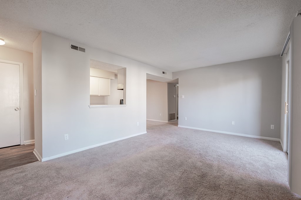 A spacious, empty room with white walls and carpeted floor.