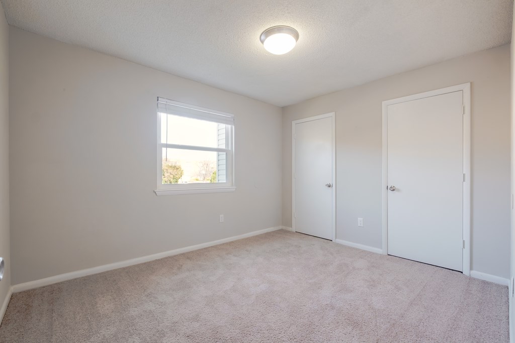 A room with a window and two doors.