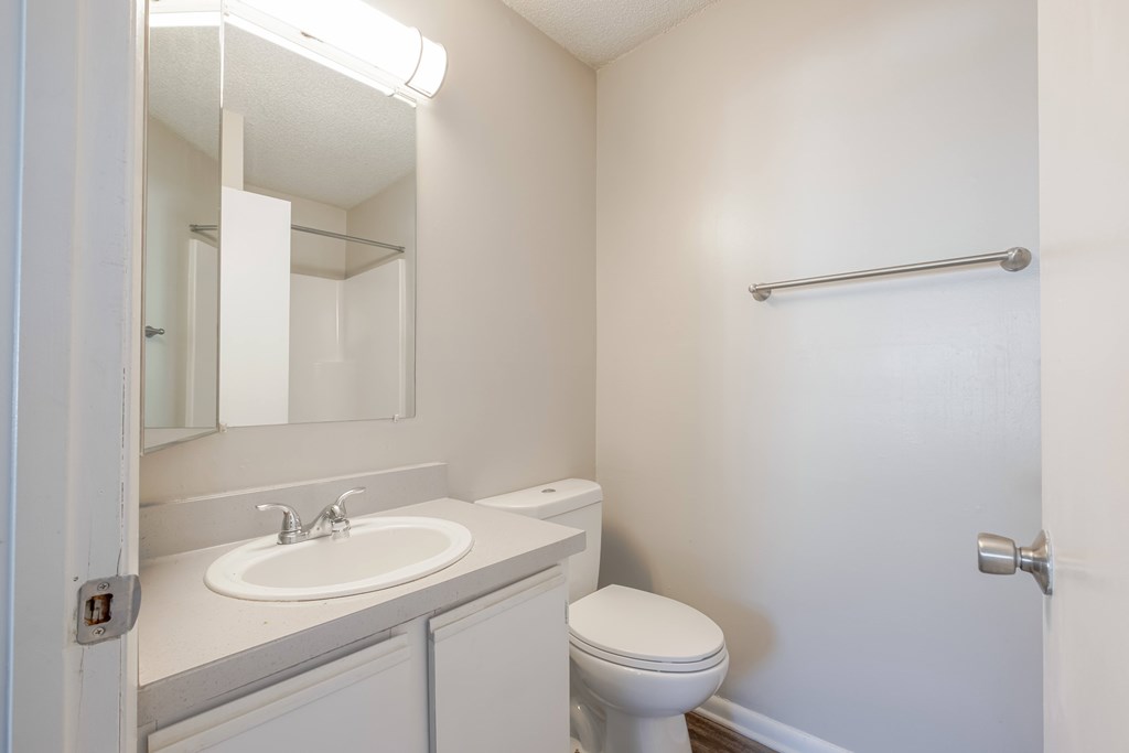 A white bathroom with a toilet, sink, and mirror.