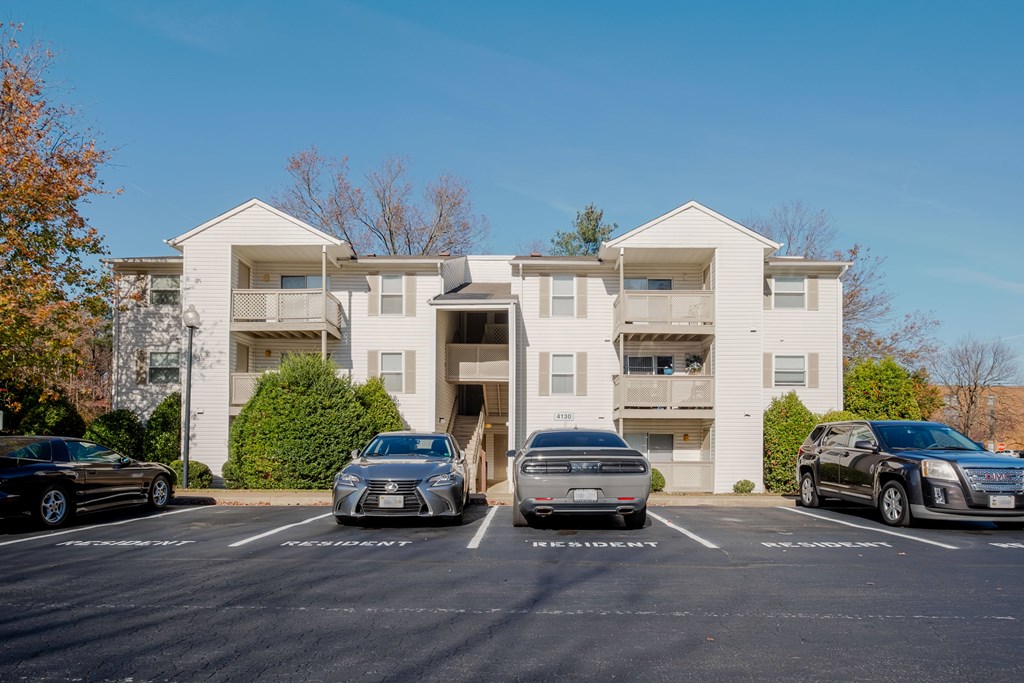 A white apartment building with cars parked in front.