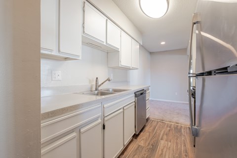 A kitchen with white cabinets and a stainless steel refrigerator.