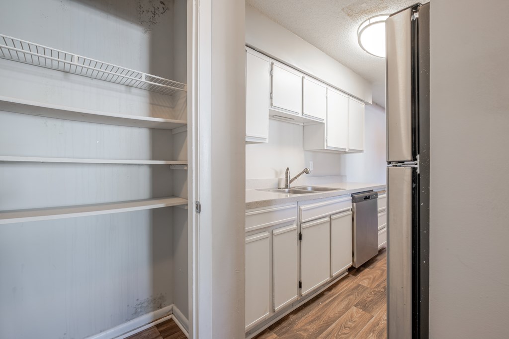 A kitchen with white cabinets and a refrigerator.